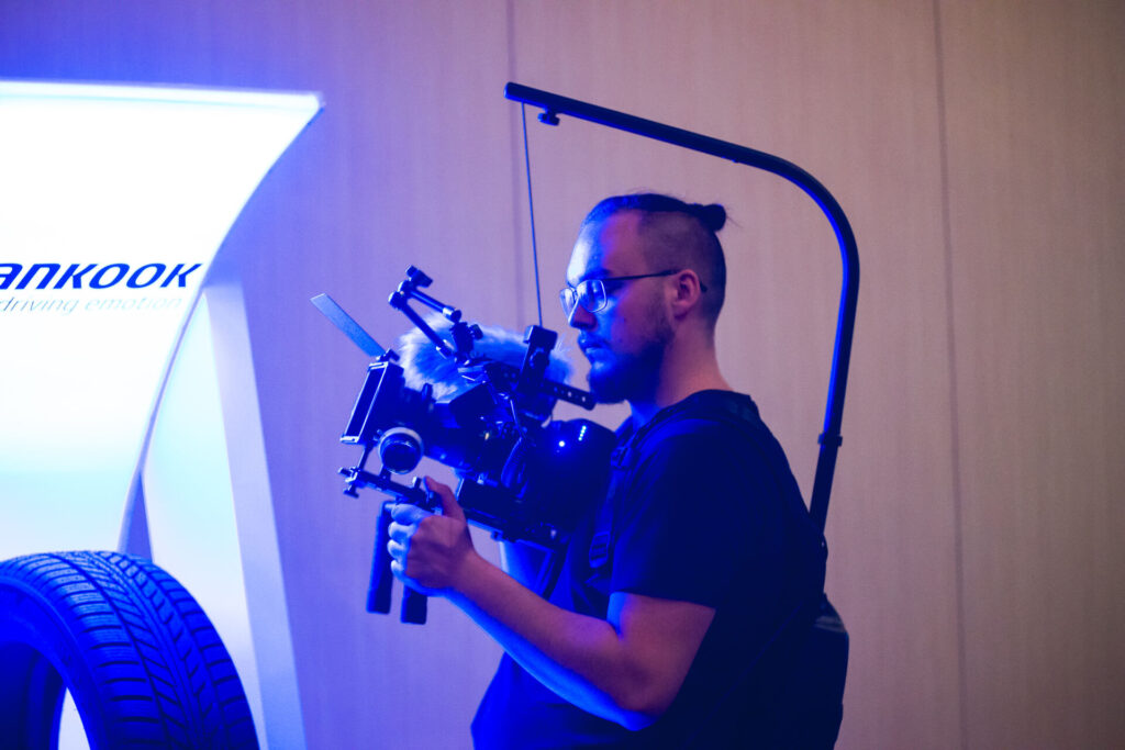 Kamerzysta z DXM Studio podczas produkcji filmu promocyjnego z profesjonalnym sprzętem w trakcie wydarzenia.